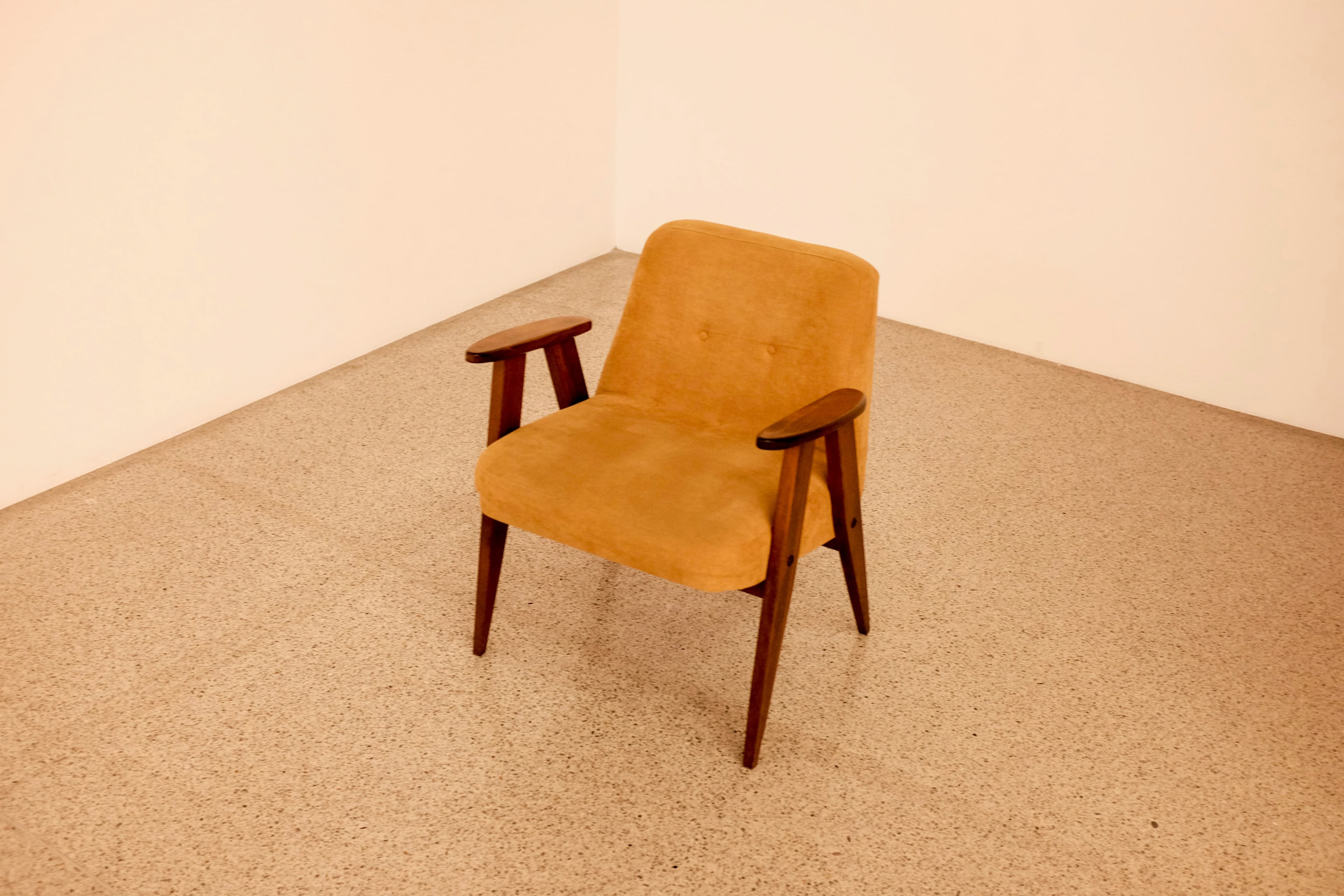 Mid-century lounge chair with cognac upholstery and a turned walnut frame, on a beige sisal floor.