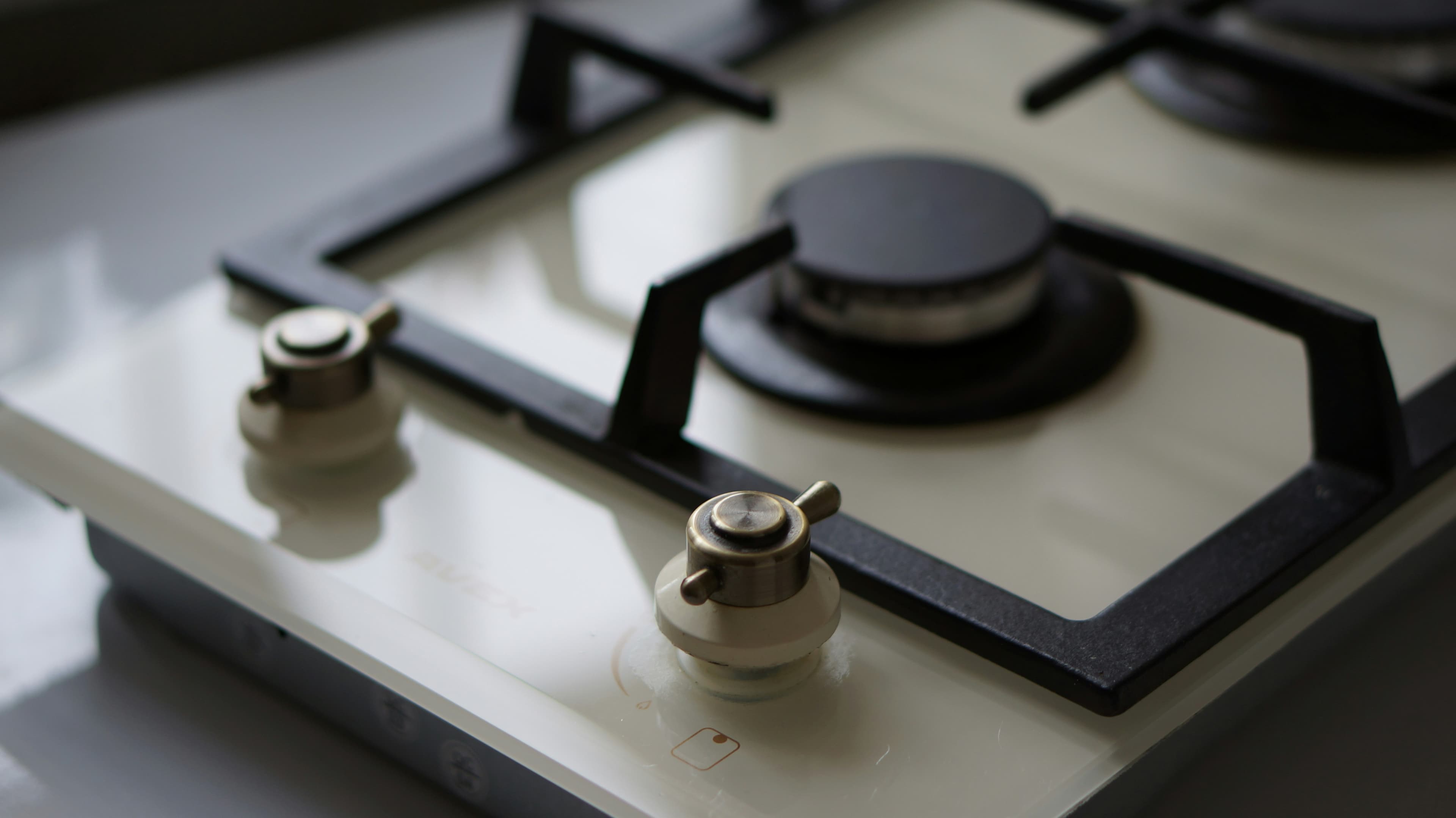 Close-up of a stainless steel four-burner gas hob with brass control knobs.
